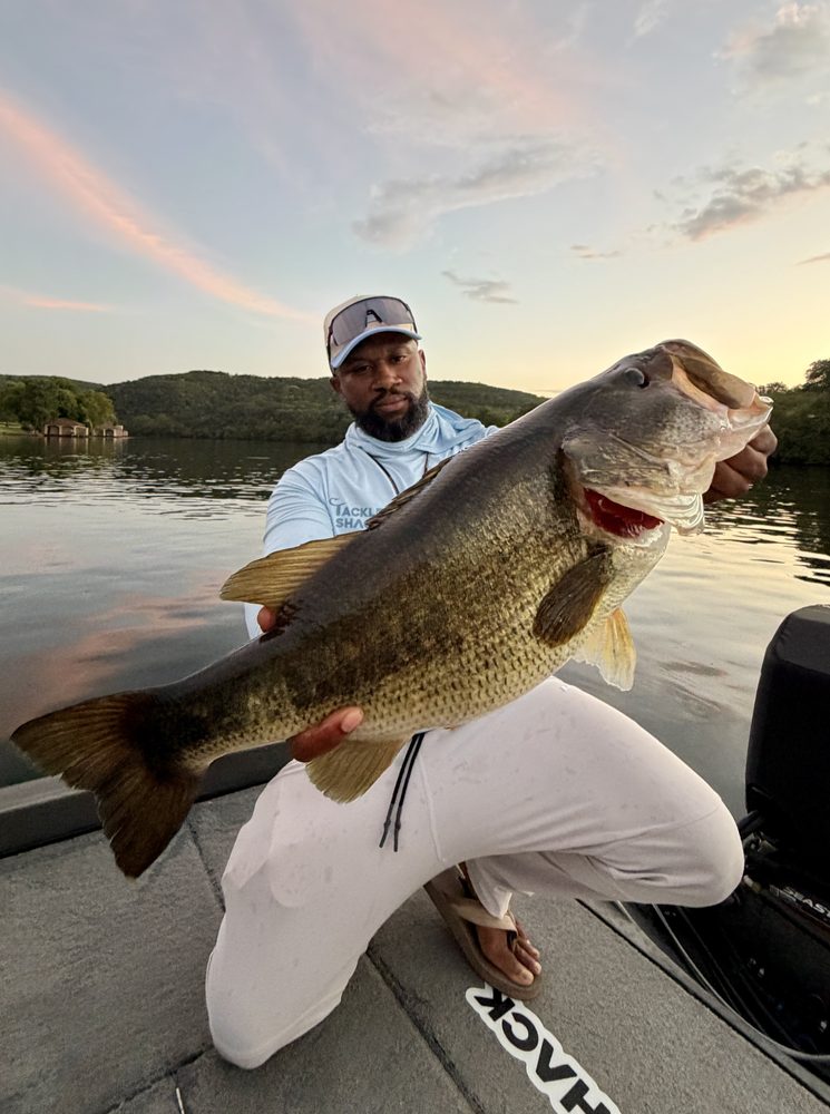 Chase Powell holding a trophy largemouth bass at sunset