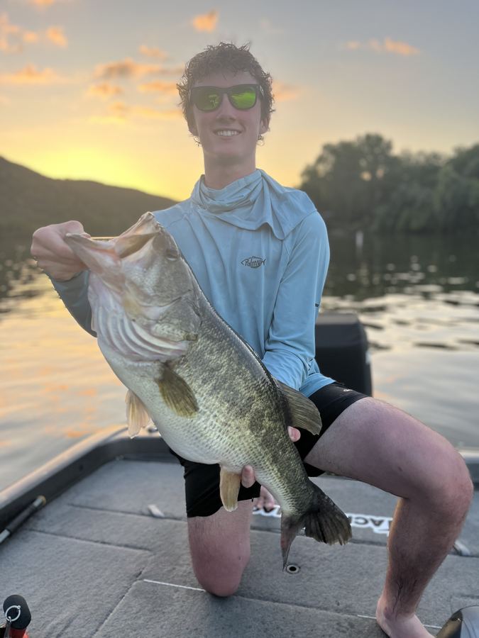 Smiling client holding a big largemouth at golden hour