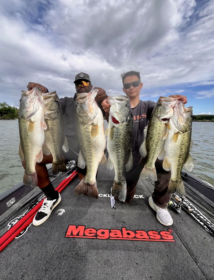 Guide and client showing off four largemouth bass on the deck
